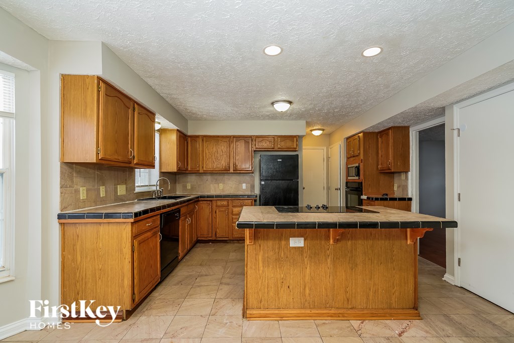 A kitchen with wooden cabinets and a black countertop.