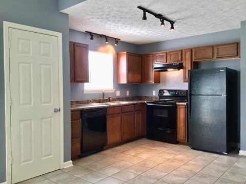 A kitchen with black appliances and brown cabinets.
