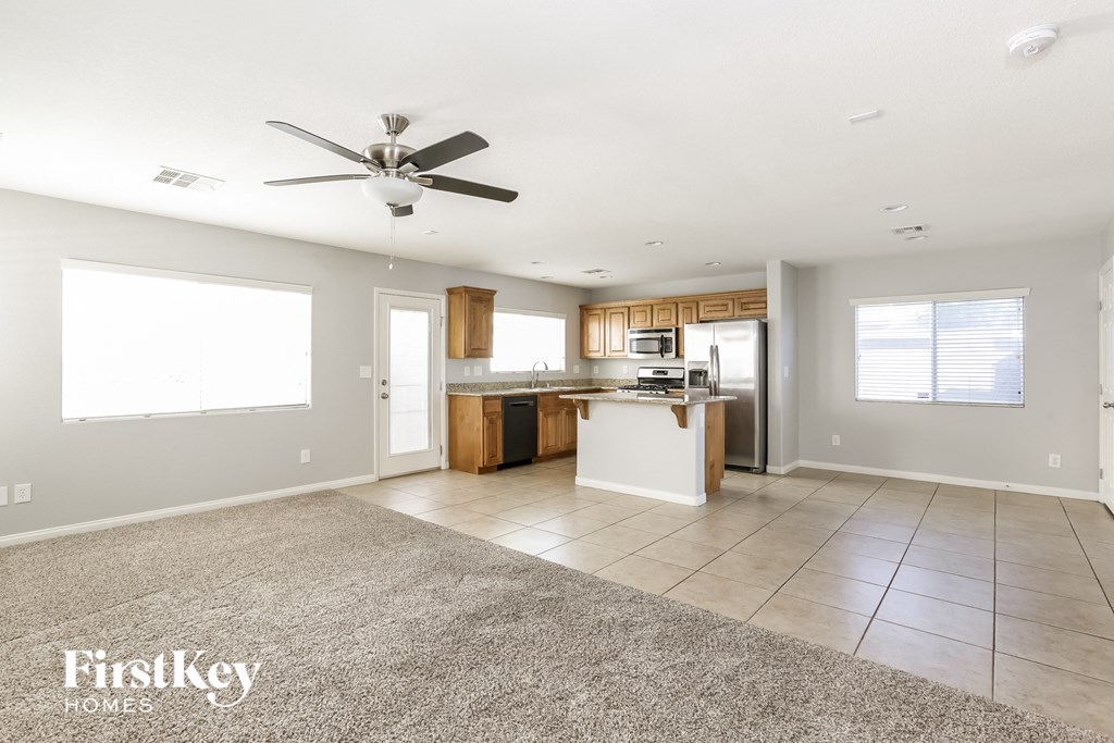 A spacious kitchen and living room with a fan on the ceiling.