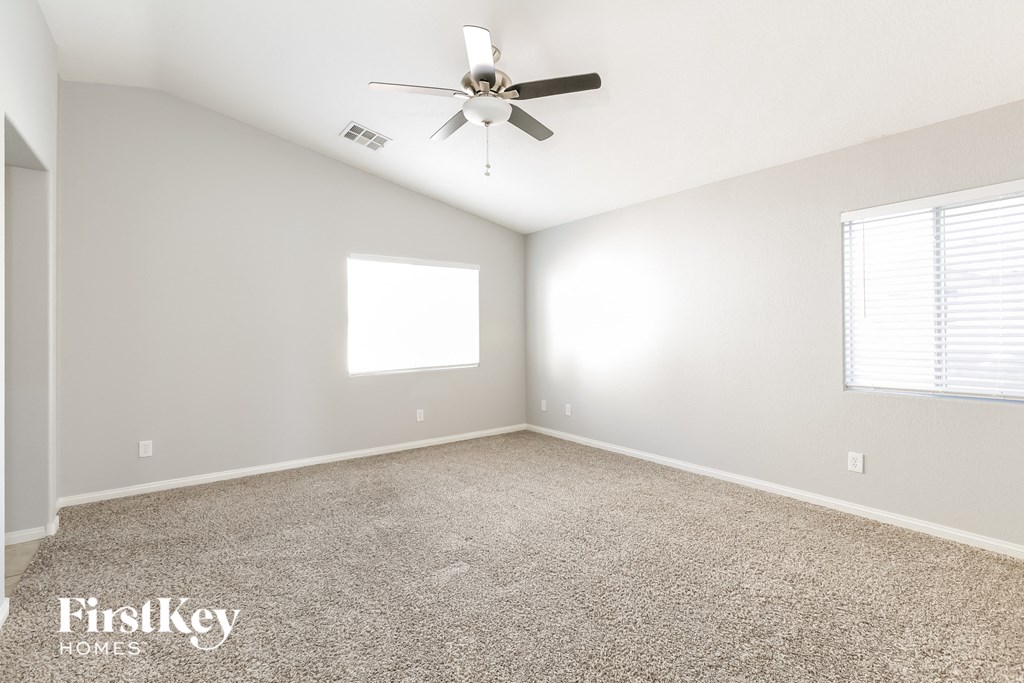 A spacious room with a ceiling fan and carpeted floor.