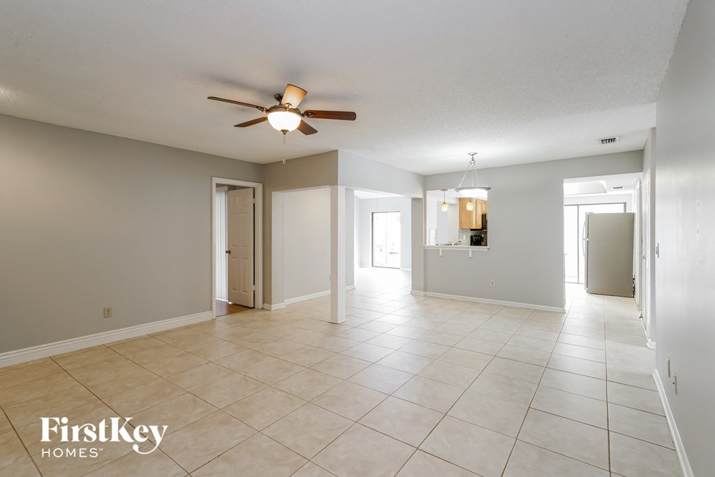 an empty living room with a ceiling fan and a tiled floor