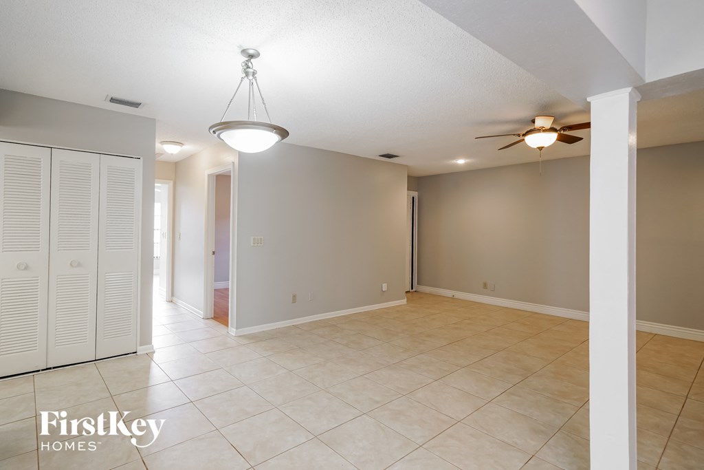 an empty living room with a ceiling fan and a closet