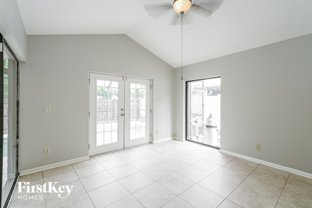 an empty living room with two doors and a ceiling fan