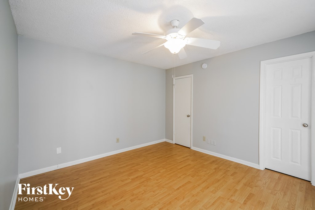 a bedroom with wood flooring and a ceiling fan