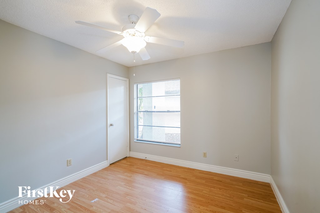 a bedroom with wood floors and a ceiling fan