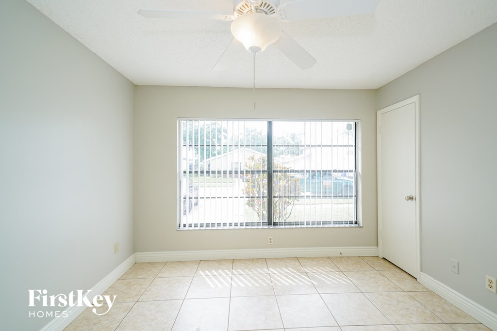 a living room with a large window and a ceiling fan