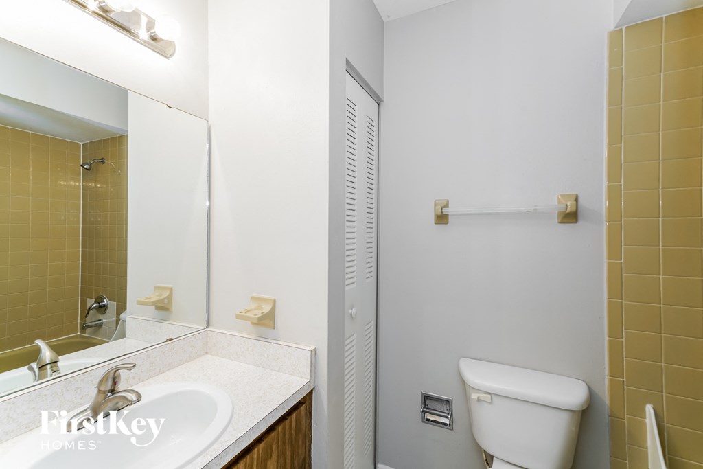a bathroom with a toilet sink and mirror and a shower