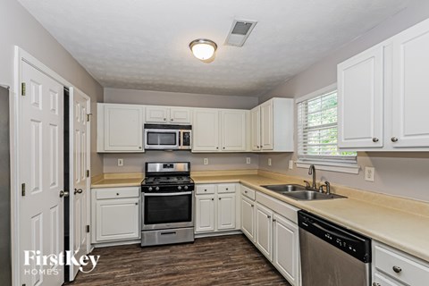 A kitchen with white cabinets and a stove top oven.