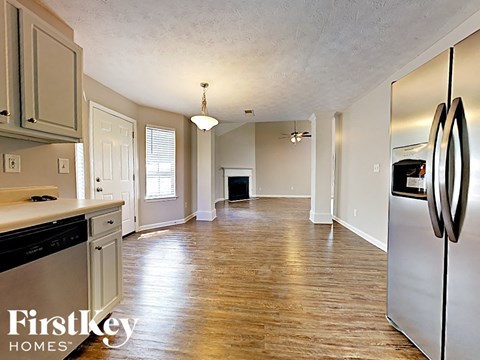 A kitchen with wooden floors and a refrigerator on the right.