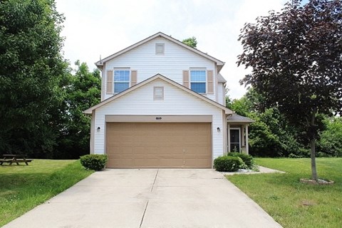 A two-story house with a garage door and a driveway.