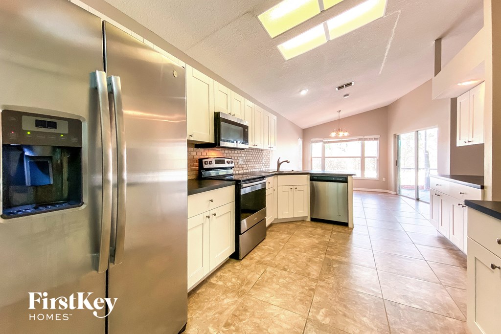 the kitchen has stainless steel appliances and white cabinets