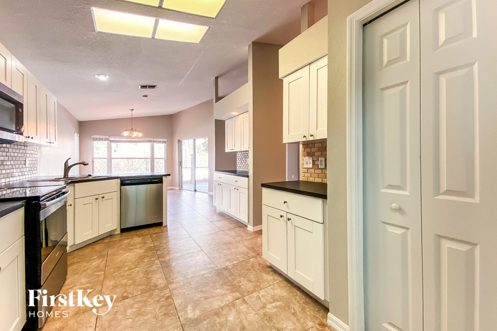 a large kitchen with white cabinets and black counter tops