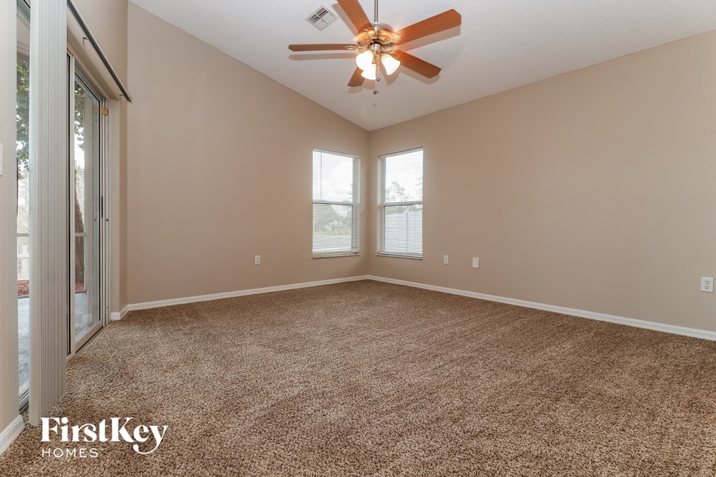 an empty living room with carpet and a ceiling fan