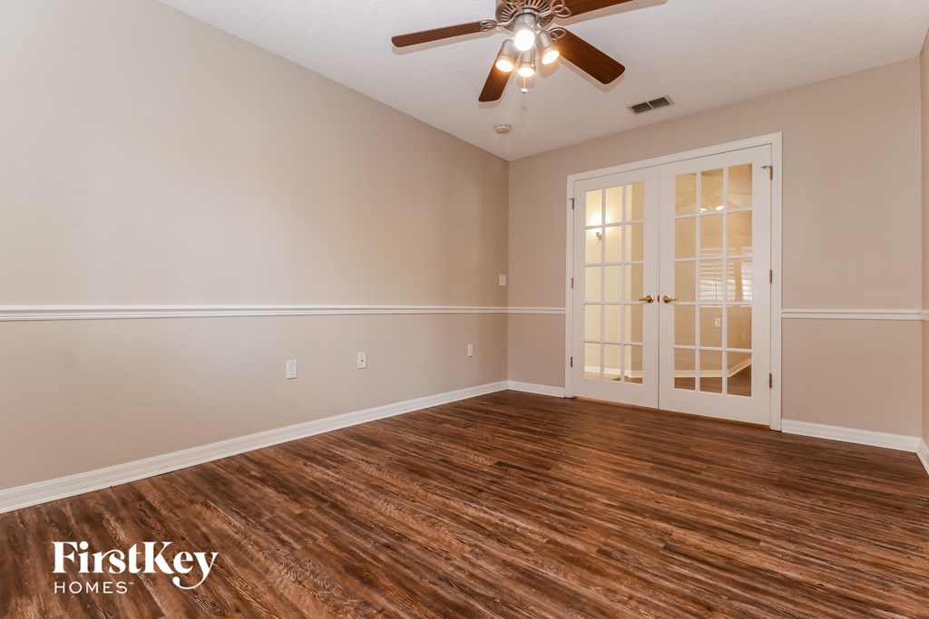 the living room of this home has a hard wood floor and a ceiling fan