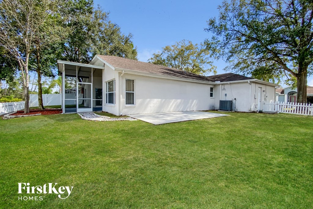 a small white house with a lawn and a white fence