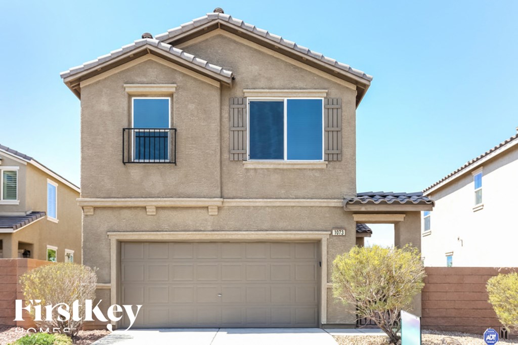 A beige house with a garage door and a window with a balcony.