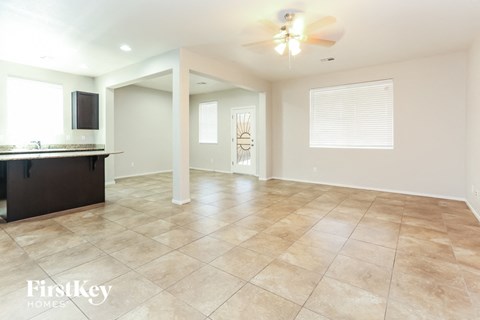 A spacious room with a kitchen area and a ceiling fan.