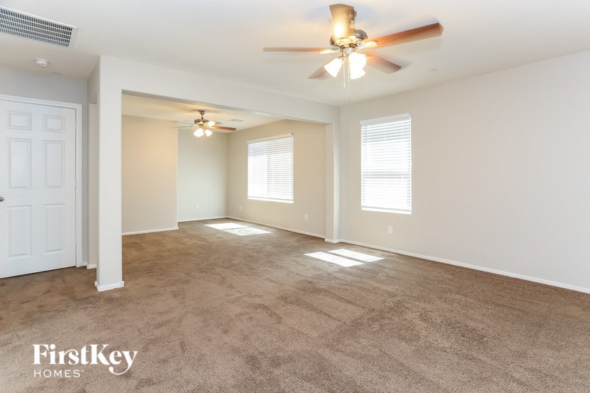 A spacious room with a ceiling fan and two windows.
