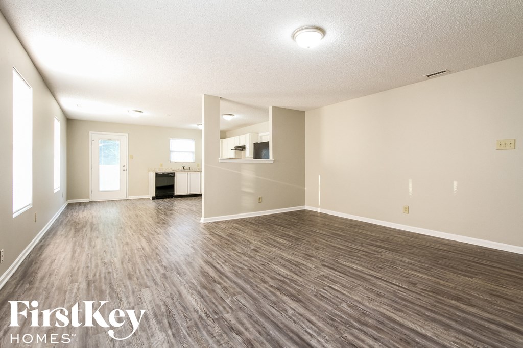 A spacious room with wooden flooring and a white ceiling.