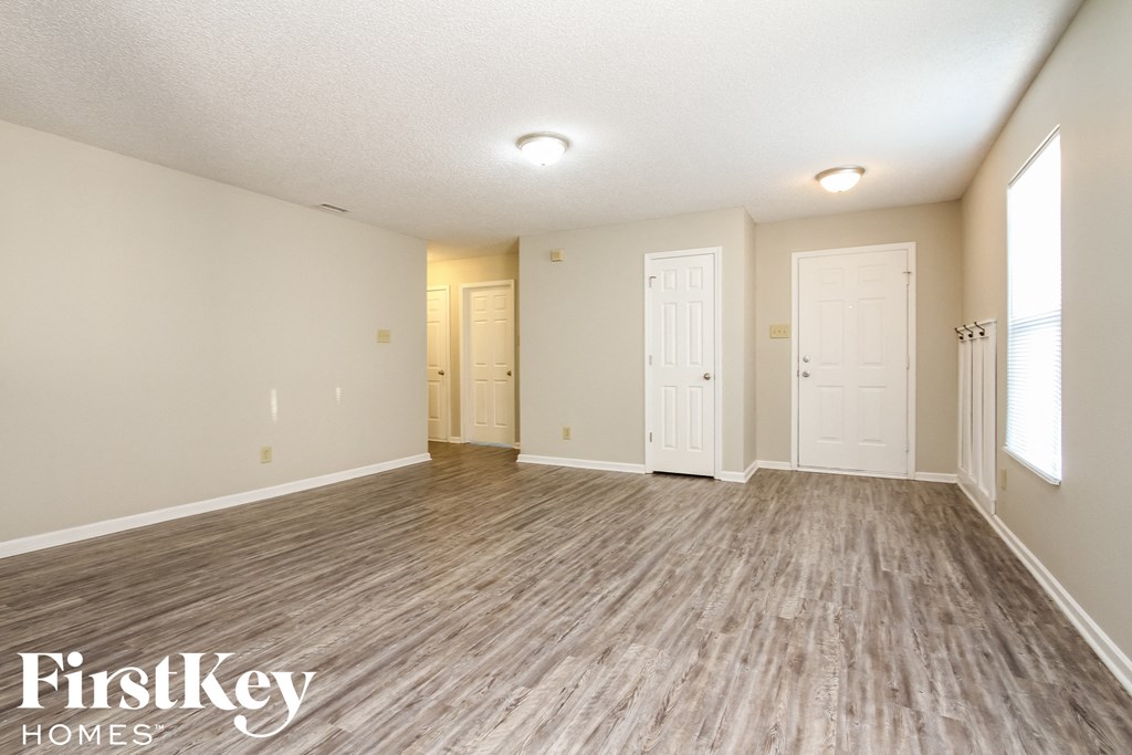 A spacious room with wooden flooring and white walls.