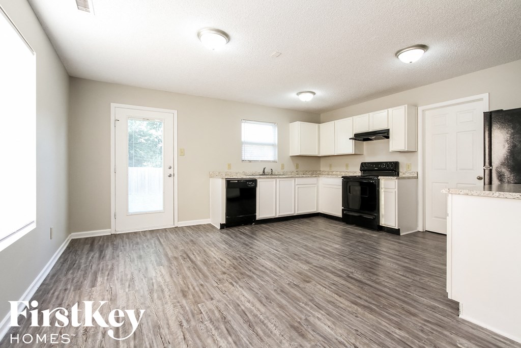 A kitchen with white cabinets and a wooden floor.