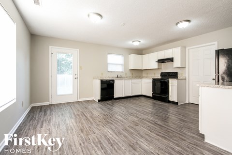 A kitchen with white cabinets and a wooden floor.