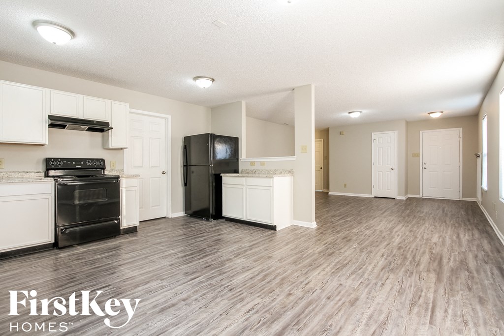 A spacious kitchen with white cabinets and a black fridge.
