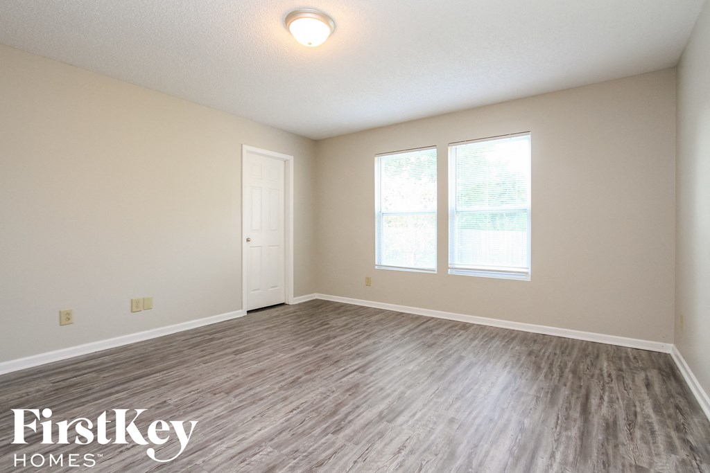 A room with a wooden floor and a window with a view of trees.