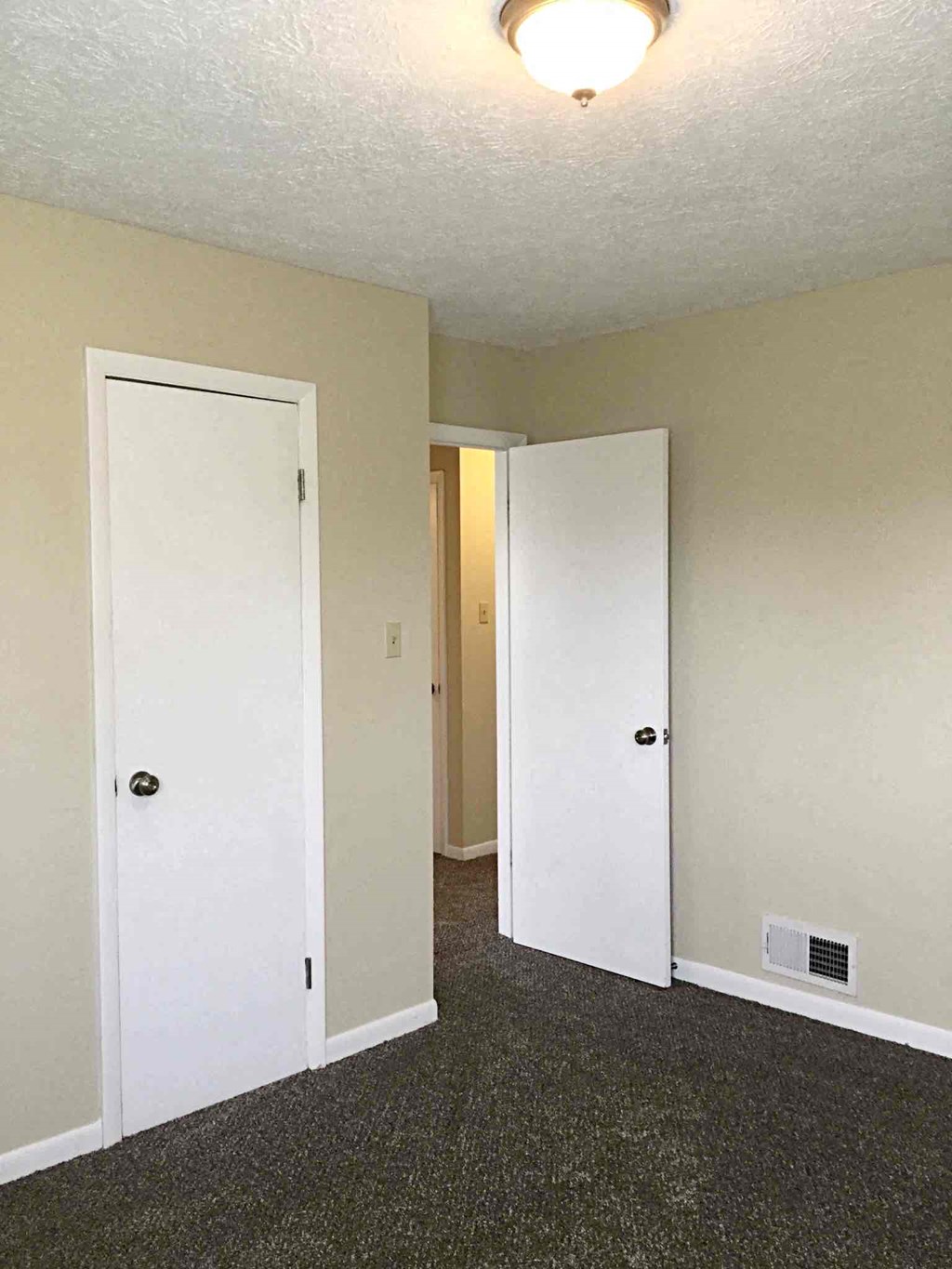 an empty room with a door open to a hallway and a closet