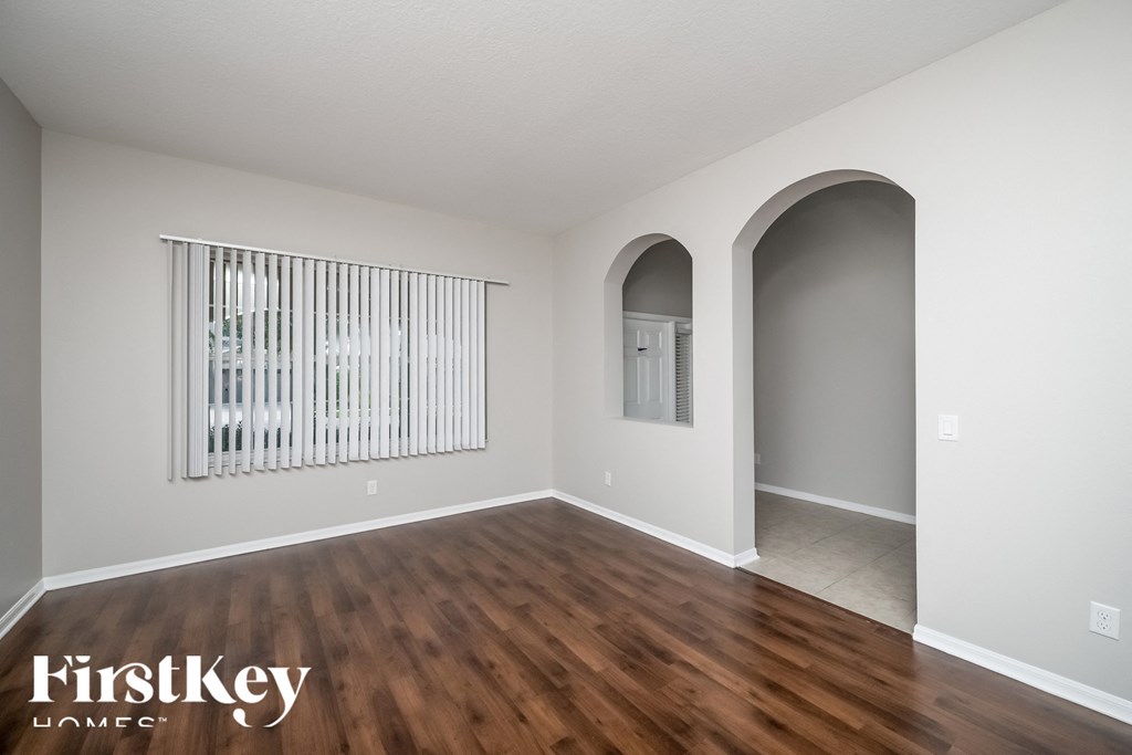 A room with wooden floors and a window with blinds.