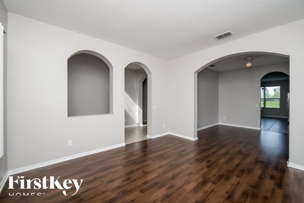 A spacious room with wooden floors and arched doorways.