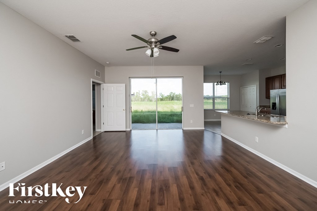 A spacious room with wooden floors and a ceiling fan.