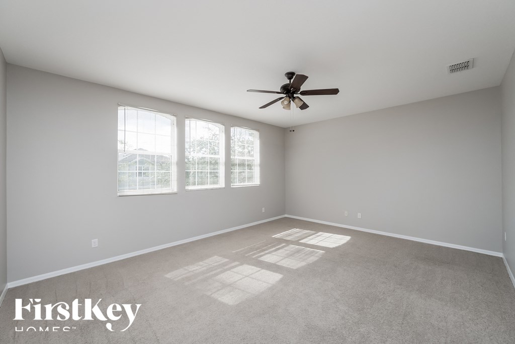 A spacious room with a ceiling fan and large windows.