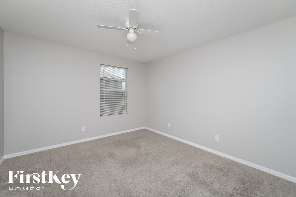 A spacious room with a carpeted floor and a ceiling fan.
