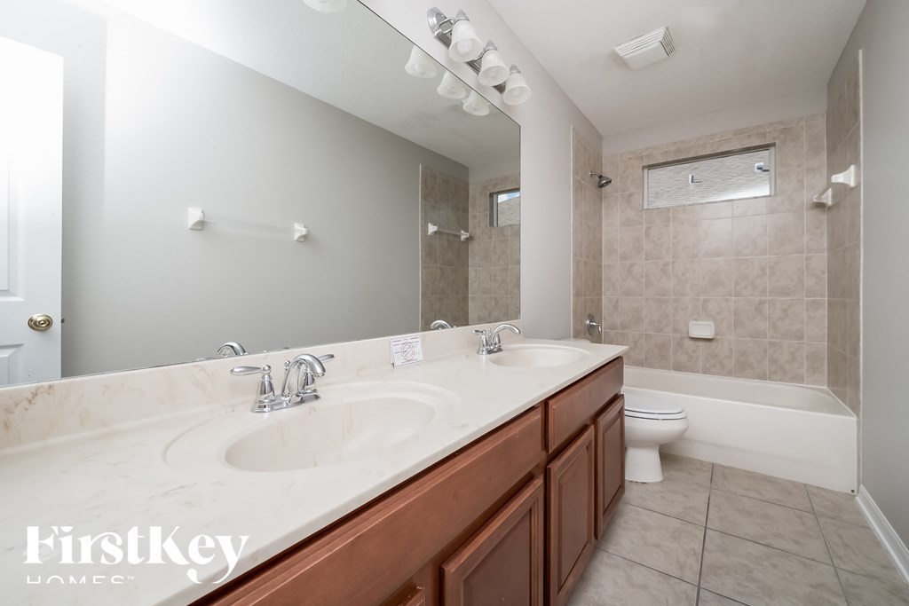 A bathroom with a double sink vanity and a toilet.