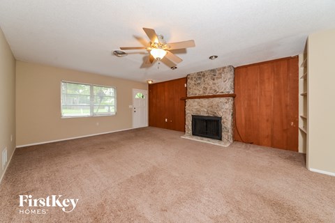 A living room with a fireplace and a ceiling fan.
