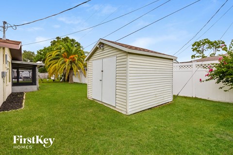 A small white shed sits in a grassy yard.