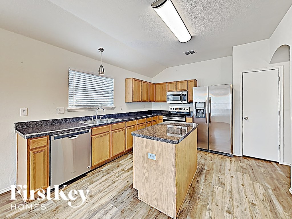 an updated kitchen with wood floors and stainless steel appliances