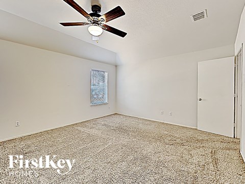 the spacious living room has a ceiling fan and a carpet