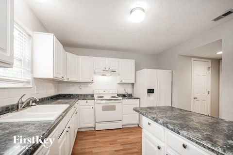 A kitchen with white cabinets and a marble countertop.