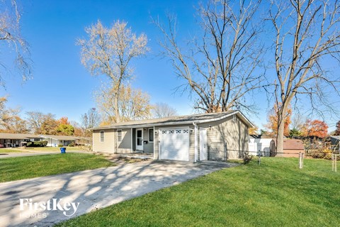 a small gray house with a driveway and a garage door