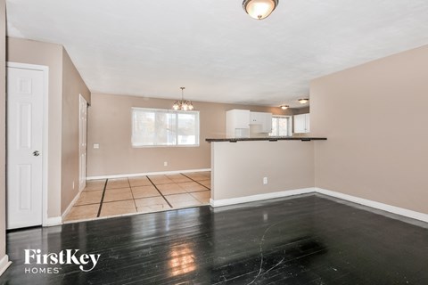 the living room and kitchen of a home with black vinyl flooring