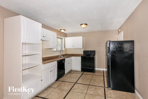 a kitchen with white cabinets and a black refrigerator