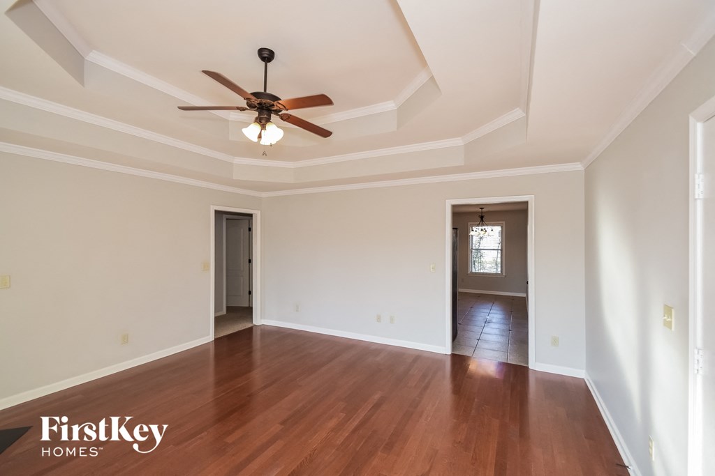 A room with a ceiling fan and wooden floors.
