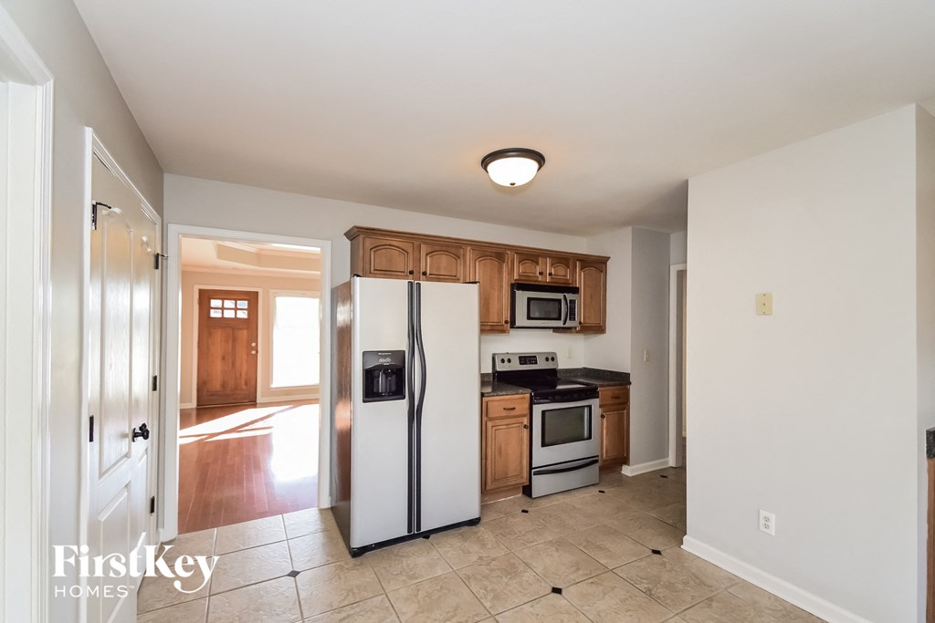 A kitchen with a refrigerator, microwave, and oven.