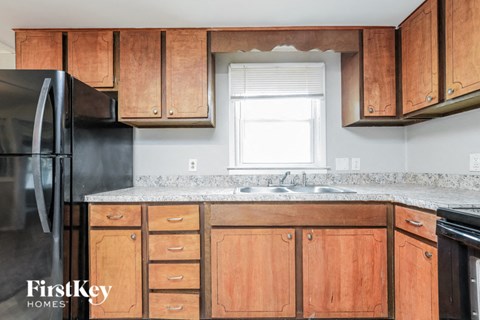A kitchen with wooden cabinets and a black refrigerator.
