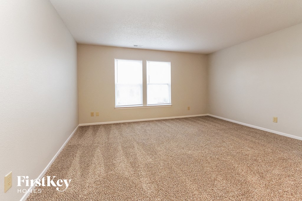 a spacious living room with carpet and a window