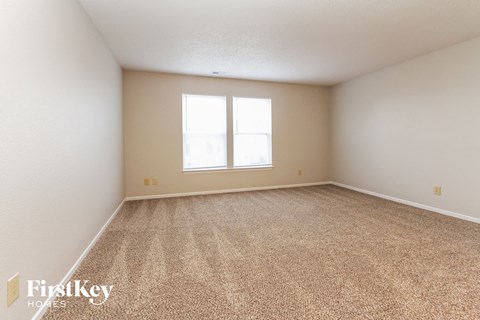 a spacious living room with carpet and a window