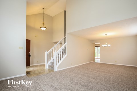 A spacious room with a staircase and a chandelier.