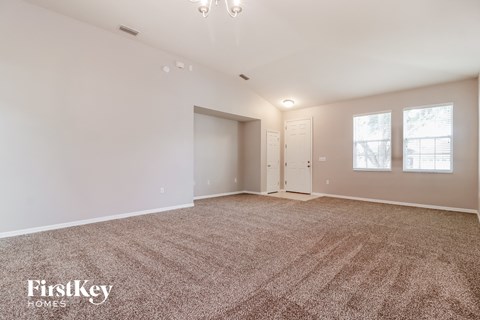 A spacious room with a carpeted floor and a chandelier hanging from the ceiling.